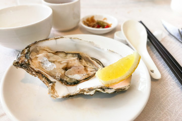 Fresh live raw oyster served with lemon and chili sauce