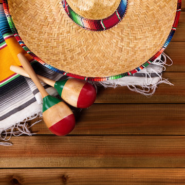 Mexico cinco de mayo background border square format with sombrero straw hat traditional rug or blanket and maracas on an old dark wood background fiesta carnival photo