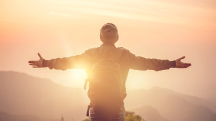 Carefree Happy Man Enjoying Nature on top of mountain cliff with morning sunrise outdoor, Freedom...