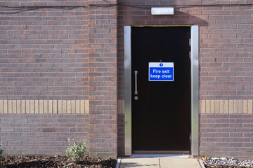 Fire exit emergency keep clear sign on hotel door for safety of workers guests people