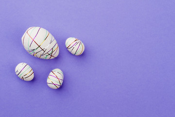 Four decorative Easter eggs and copy space. Styrofoam eggs with ribbons on purple background, text space. How to decorate Easter eggs.