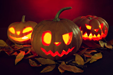 Halloween pumpkin lantern with dry leaves with burning candles