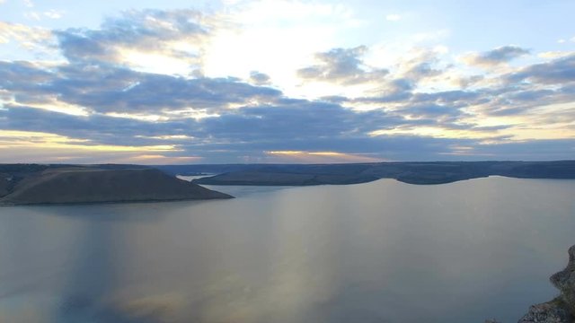 Great sunset on the lake between the mountains. A couple hugging at the edge of the cliff. 4k