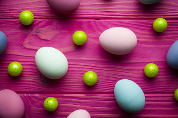 Fototapeta na wymiar Colored Easter eggs and green balls on pink wooden background