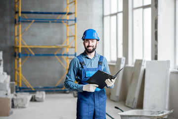 Builder or foreman in working uniform expertising the structure standing with folder at the...