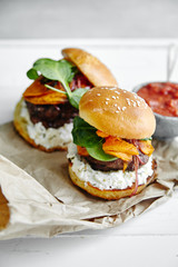 Burgers with grilled beef patties, cream cheese and spinach on classical bun. White wooden background