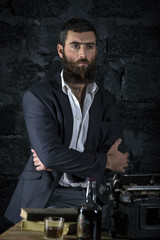 Fototapeta na wymiar On chair sitting serious businessman. Dark hair and beard wearing jacket. Against the wall.