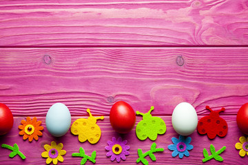 Easter background - colored eggs and colorful decorations on pink wooden background