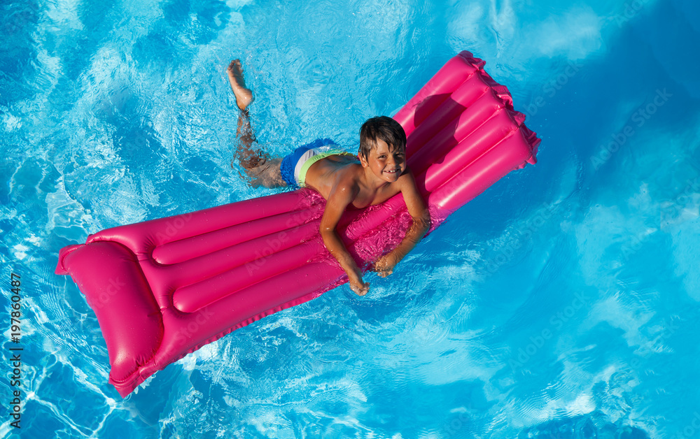 Wall mural happy boy swimming on pink inflatable mattress