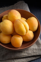 Fototapeta na wymiar Sweet apricots in bowl on linen and black slate stone