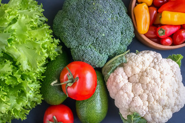 Mixed vegetables of cauliflower and broccoli, garlic, green onions, tomatoes and green peas on a wooden background in rustic style.