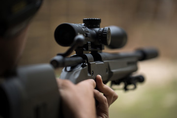 Sniper shooting rifle by looking through a scope. - obrazy, fototapety, plakaty