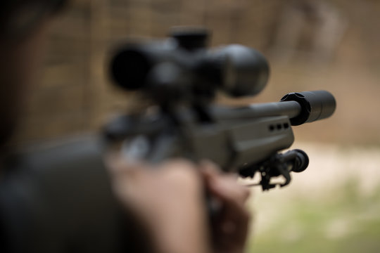 Sniper shooting rifle by looking through a scope.