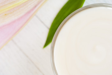 Cosmetic cream and lily flower on white wooden table