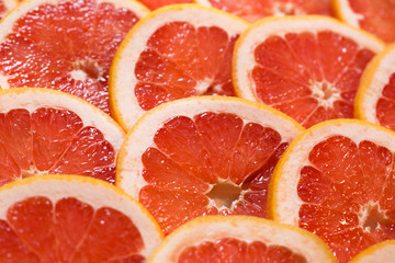 Bright red background with juicy slices of grapefruit. Healthy food background.