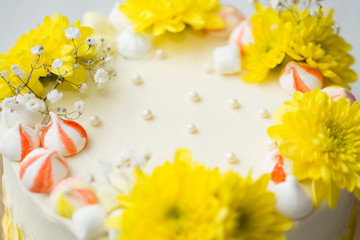 Cake with yellow stains, yellow chrysanthemums and meringue
