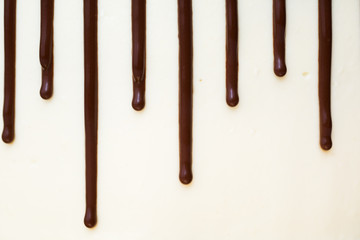 Chocolate drips on the background of white cream