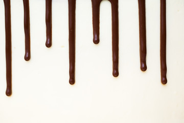 Chocolate drips on the background of white cream