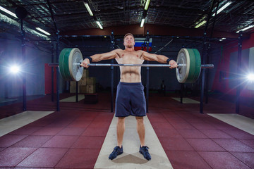 Muscular fitness man preparing to deadlift a barbell over his head in modern fitness center.Functional training.Snatch exercise.
