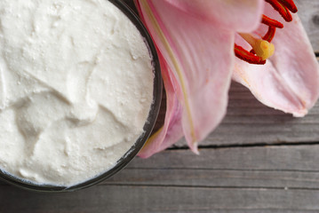 Moisturizer and lily flower on weathered wooden