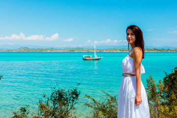 Fototapeta na wymiar Young beautiful girl posing in a hat near a boat in sea in Greece