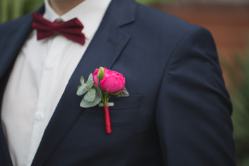 Red rose boutonniere on groom's suit