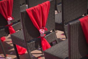 Row of wedding chairs decorated with red roses.