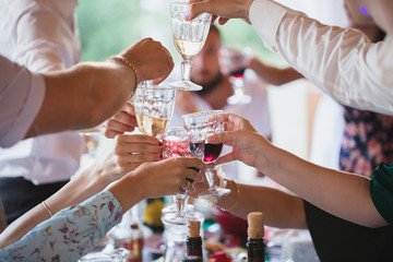 People clang glasses sitting at dinner table in sparkling lights