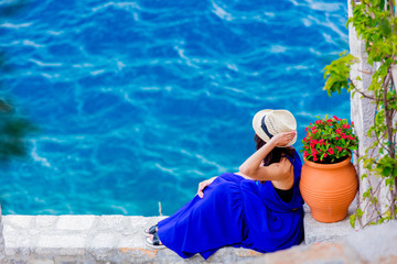 Young girl in blue dress in city of Hydra island in Greece. Summertime vacation concept