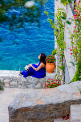 Young girl in blue dress in city of Hydra island in Greece. Summertime vacation concept