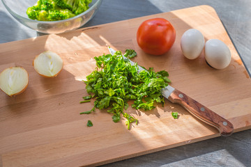 Raw chopped vegetables for a French omelette on a wooden cutting board