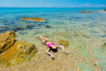 Fototapeta na wymiar Young beautiful girl in bikini on the beach in Greece. Summertime vacation concept
