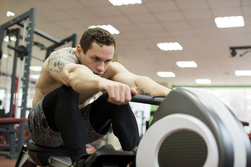 Fototapeta na wymiar Man running rowing exercise in the gym