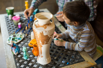Father and son paint a vase