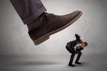 Employee is afraid of the big boss foot, which is stepping down him
