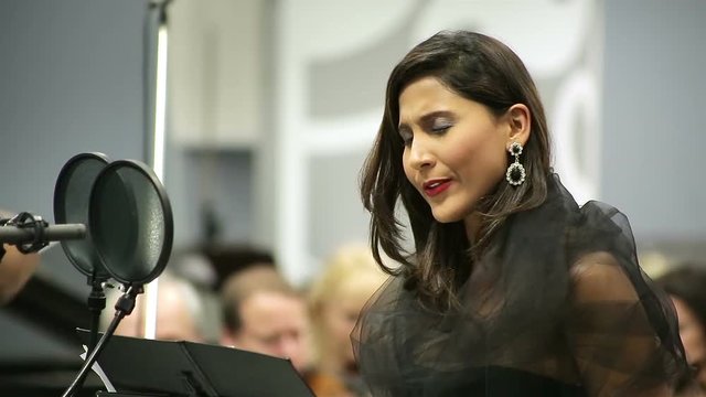 Opera singer sings in the microphone with the orchestra