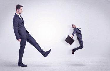 Big man in suit kicking out little himself out with simple white wallpaper
