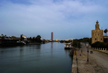 Obraz premium View of Golden Tower (Torre del Oro), Seville Tower and Guadalquivir river in cloudy day of winter. February 2018, Seville, Andalusia, Spain.