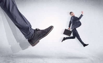 Boss mobbing his worker, illustrated by black shoe kicking small businessman who is flying away in...