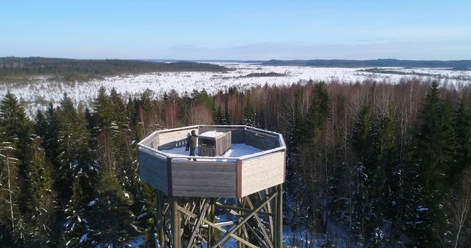 Man and a kid on a watchtower Cinema 4k aerial view around a male and a boy enjoying the view on a observation tower, on a cold sunny day, in Torronsuo national park, Kanta-hame, Finland