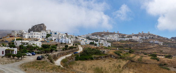 Fototapeta na wymiar A view of some white houses of Chora of Amorgos, with the windmills above them
