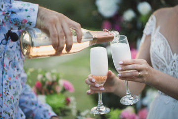 The bridegroom pours champagne in glasses.