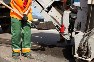 Fototapeta premium Road workers repair work. work sleeps shovel the material into the machine.
