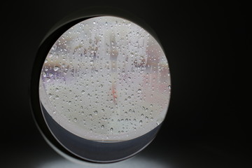 Close-up of air plane window during rain. Selective focus on raindrops
