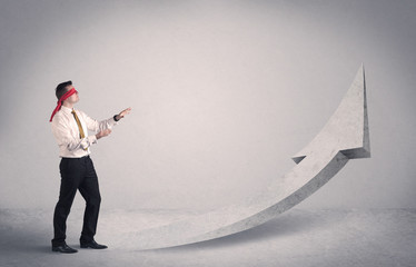 A scared blindfolded businessman forced to face a problem concept with illustrated arrow pointng to...