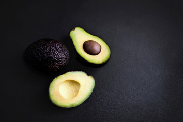Avocado on a black background. Half of avocado close up. Top view. Copy space.