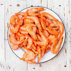 Cooked fresh  shrimps on a white plate over old white wooden table with copy space