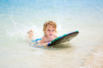 Young surfer, happy young boy in the ocean on surfboard