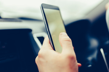 Close-up of male driver hands using mobile phone in luxury car.