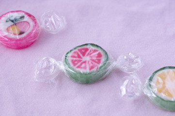 Colorful lollipops and different colored fruit round candy in wrapper on pink background